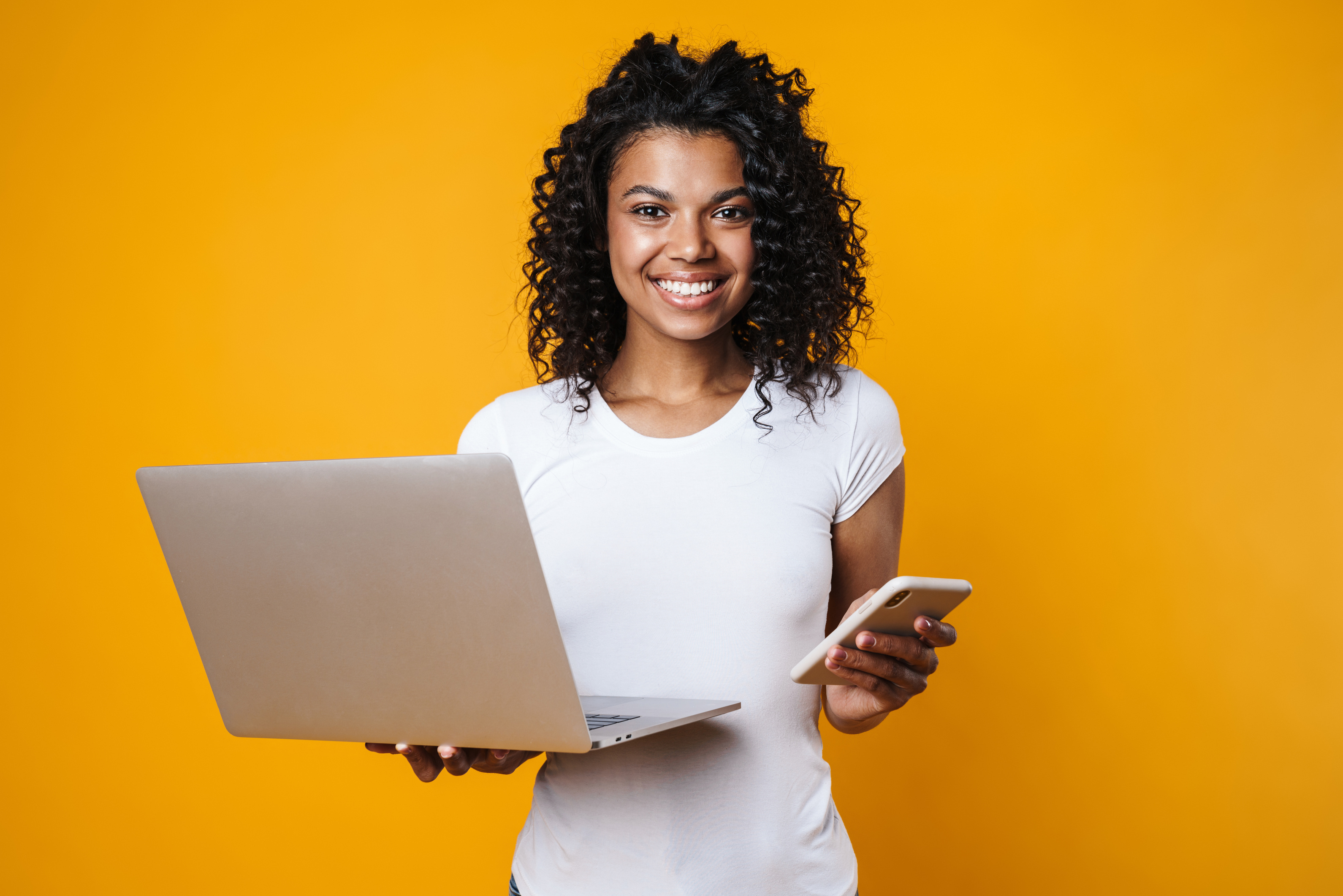 Image of Happy African American Woman Holding Cellphone and Laptop